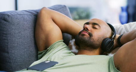 Eyes closed, headphones and peace with man on sofa for streaming service, calm audio and ambient...