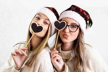 Friends in Santa hats making fun faces with holiday photo booth props