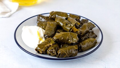 Fototapeta premium A plate of vibrant, savory grape leaves, or dolmas, are presented with a dollop of creamy sauce.