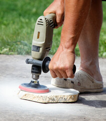 A man is using a power tool to sand a piece of wood