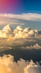 Fototapeta premium A breathtaking aerial view showcases a dramatic sky filled with fluffy, cumulus clouds, bathed in warm golden light, with mountain ranges hidden beneath a thick layer of clouds.