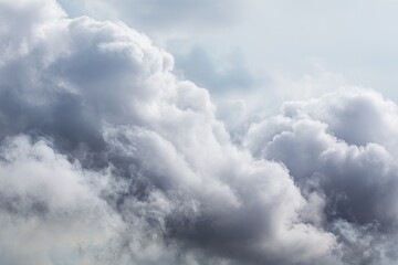 Obraz premium Soft, gray, puffy clouds fill the frame against a bright, pale sky, creating a serene, airy atmosphere