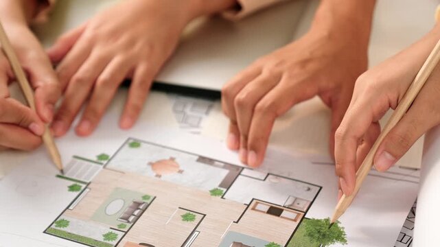 Smart architect and safety engineer discussion about building blueprint on table with architectural document, measurement tools and wooden block scatter around at modern office. Closeup. Delineation.