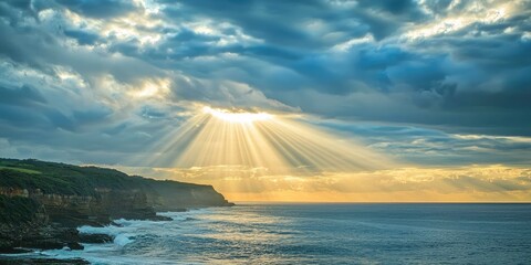 Sunlight bursting through clouds above ocean cliffs at sunrise Stock photo