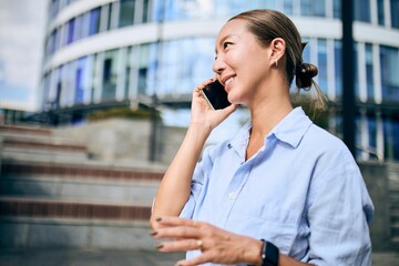 Smiling Asian Businesswoman Talking on Mobile Phone Outside Modern Office Building