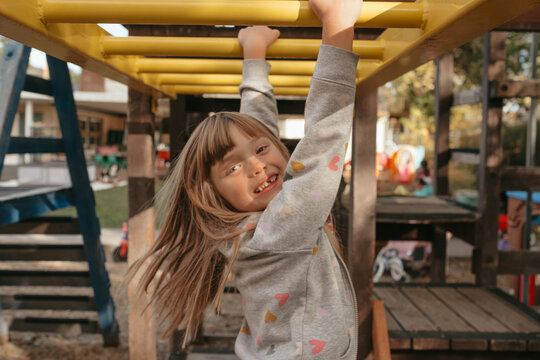 Preschool girl playing on monkey bars in autumn