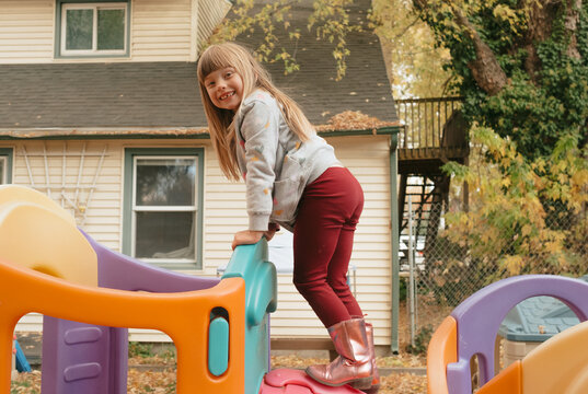 Preschool girl climbing on playground in autumn, back to school