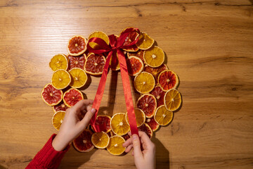Step 3 Handmade tying ribbon Christmas wreath from dried orange grapefruit slices. Festive holiday...