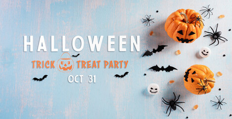 Halloween decorations made from pumpkin, paper bats and black spider on pastel blue background. Flat lay, top view with copy space for text.
