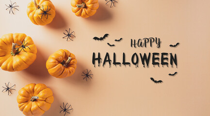 Halloween decorations made from pumpkin and black spider on pastel orange background. Flat lay, top view with copy space for text.