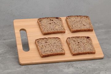 Four slices of whole wheat rye bread lying on a wooden chopping board