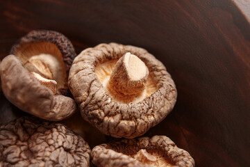 Dried edible shiitake mushrooms in a rustic wooden bowl. 