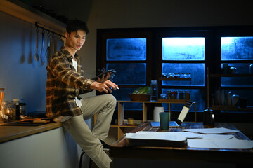 A man works late at night in a dimly lit kitchen.