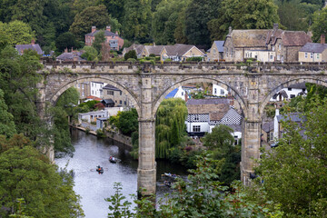 Fototapeta premium Scenic view of the historic stone viaduct crossing the River Nidd in Knaresborough, North Yorkshire, with houses and trees along the riverside