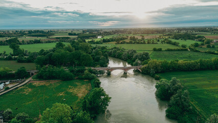 Fototapeta premium Captivating aerial view of the serene Oglio river winding through the picturesque countryside of Pontevico Brescia Italy showcasing lush green fields and tranquil water during a beautiful day