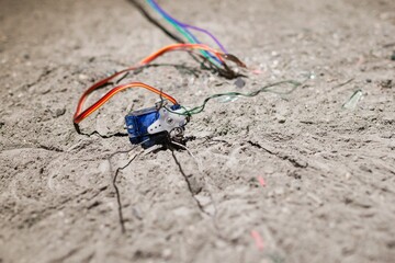 Electronic Component Surrounded by Wires on Rough Concrete Surface, Close-Up View, Technical Concept