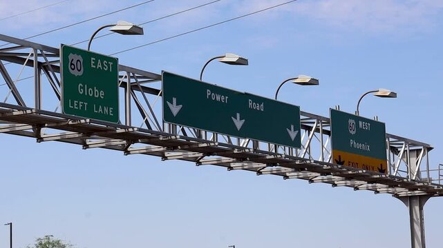 Overhead freeway sign directs drivers toward Globe, Power Road, and Phoenix under blue skies