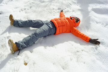 Relaxed traveler in winter clothes lying on fresh snow, enjoying peaceful moment of mindfulness in...