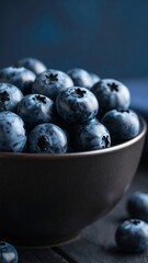 Freshly picked blueberries in a dark bowl on a rustic wooden table