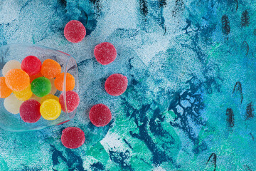Colorful marmalade candies in a glass, on the blue background