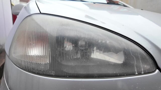 old car headlight. reflector headlight. halogen light. Matte headlight of an old SUV close-up. Dirty headlight and bumper of a white automobile.