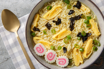 Saimin is a true Hawaiian comfort dish soft, springy noodles with nori, omelette, kamaboko and green onions closeup in the plate on the table. Horizontal top view from above