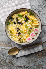 Saimin Hawaiian Ramen noodle soup with nori, omelette, kamaboko and green onions closeup in the plate on the table. Vertical top view from above