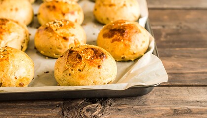 Golden-brown baked rolls on parchment paper, arranged on a baking sheet atop a wooden surface