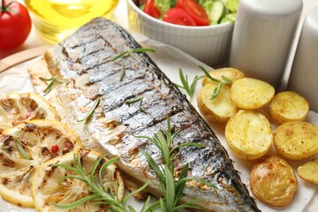 Tasty roasted mackerel served with spices and vegetables on table, closeup. Homemade seafood dish