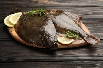 Fresh flounder fish, lemon and rosemary on wooden table, closeup. Raw seafood