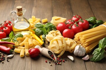 Different types of raw pasta, products and spices on wooden table, closeup