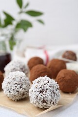 Delicious homemade candies with cocoa powder and coconut flakes on table, closeup