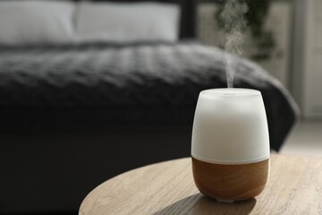 Modern aroma lamp on wooden table indoors. Space for text