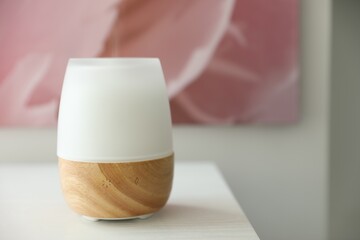 Modern aroma lamp on white wooden table, closeup. Space for text