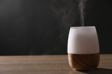 Modern aroma lamp on wooden table indoors. Space for text