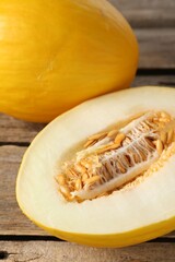 Cut and whole ripe melons on wooden table, closeup