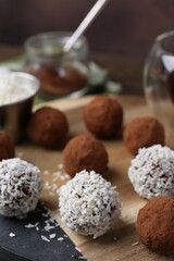 Delicious homemade candies with cocoa powder and coconut flakes on wooden table, closeup