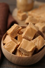 Homemade caramel candies in bowl on wooden table, closeup