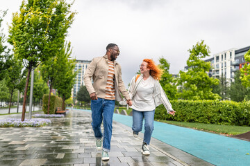 Joyful couple enjoying a walk in the park on a rainy day with vibrant greenery and stylish outfits