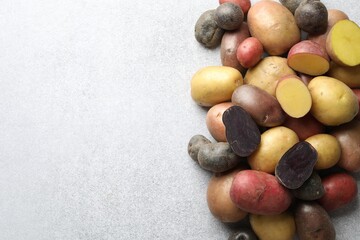 Different types of potatoes on grey table, flat lay. Space for text