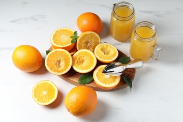Freshly squeezed orange juice, fruits and juicer on white table