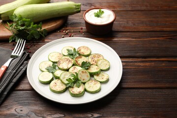 Delicious fried courgette slices with parsley served on wooden table