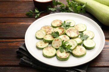 Delicious fried courgette slices with parsley on wooden table, closeup