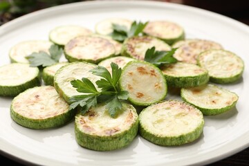 Delicious fried courgette slices with parsley on plate, closeup