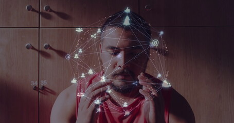 Interacting man wearing red sleeveless shirt projecting hologram network at studio, with lit icons
