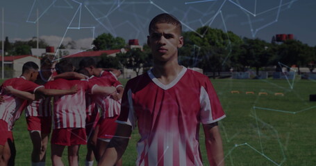 Posing soccer player in red-white uniform on field with orange hurdles, constellation overlay