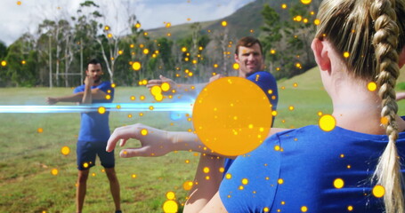 Stretching female fitness participant raising arm across chest in grassy field, with glowing orbs