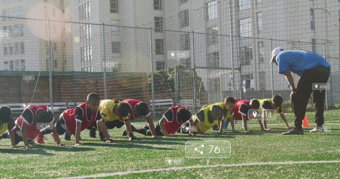 Youth soccer players wearing bibs performing push-ups on turf, with coach guiding and orange cones - Powered by Adobe