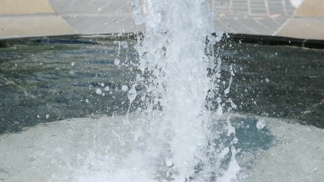 吹きあがる公園の噴水の水しぶき　夏の街の風景　暑い日差しを受けて風に煽られる水滴
