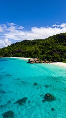 Idyllic tropical beach scene, turquoise water, white sand, lush green hills under a vibrant blue sky